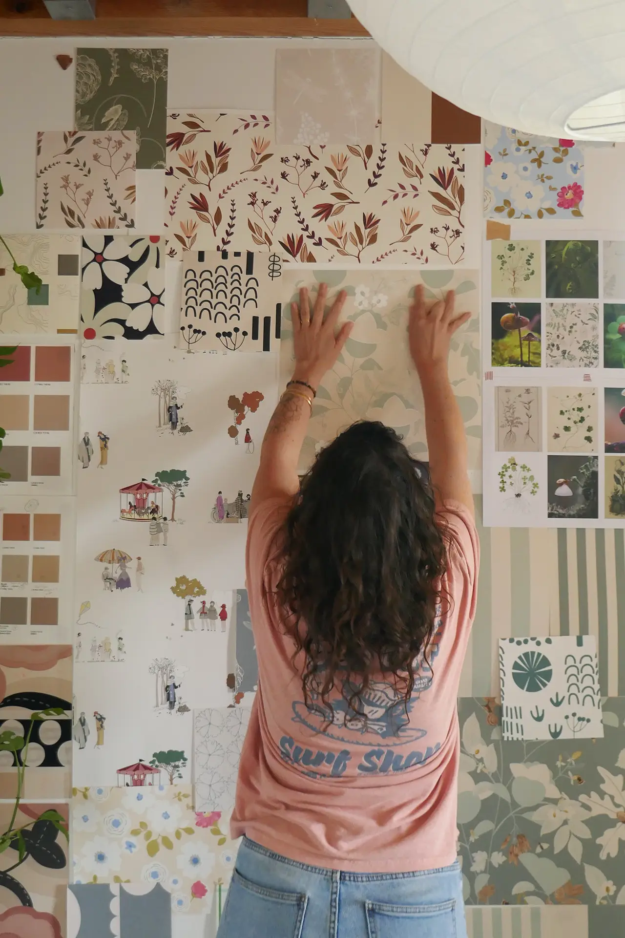 Photo de Marion, fondatrice de Paulette intérieurs devant son moodboard de ses créations de papiers peints.