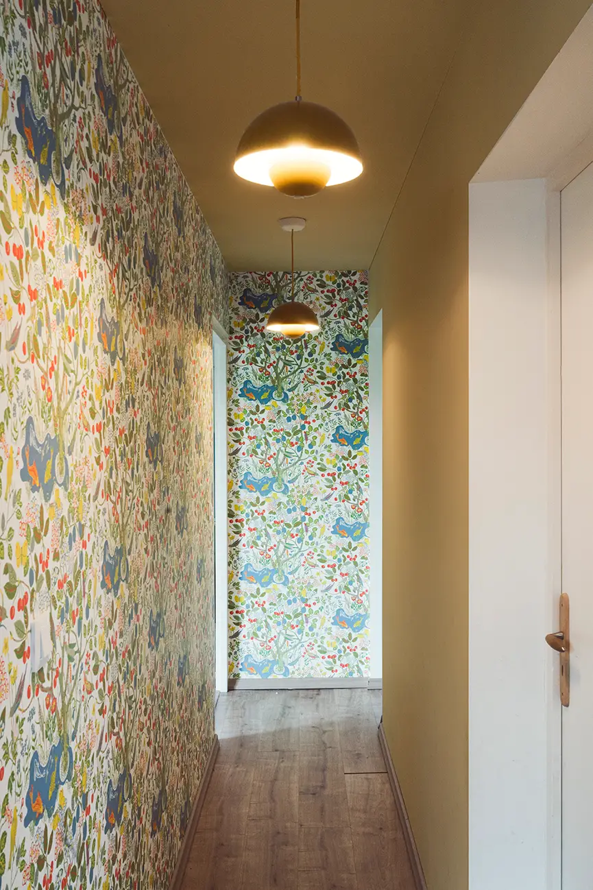 Couloir d'une maison avec son papier peint joyeux et coloré et ses murs peints en jaune chaleureux.