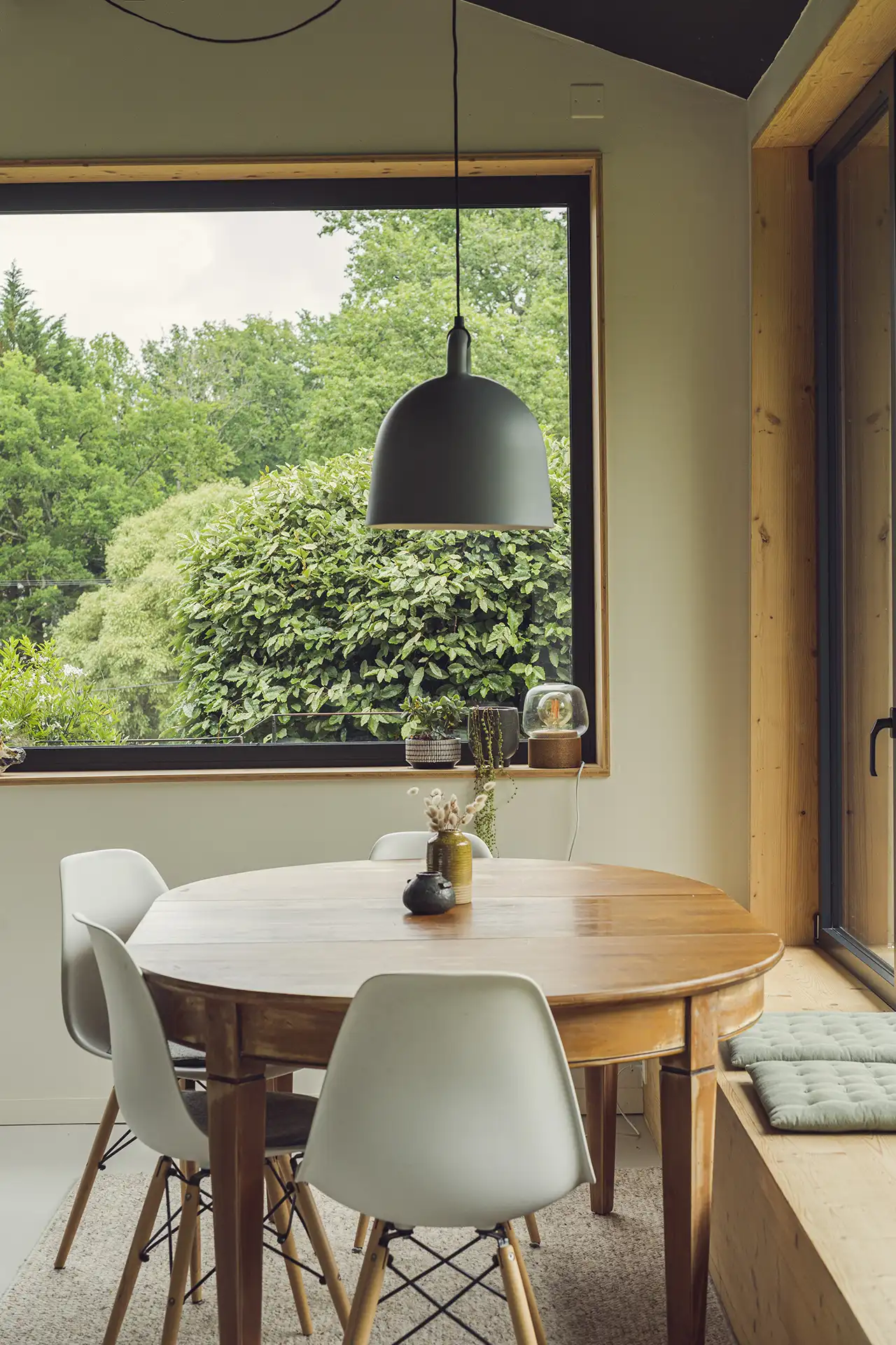 Salle à manger au style minimaliste scandinave avec ses grandes ouvertures vers le jardin.