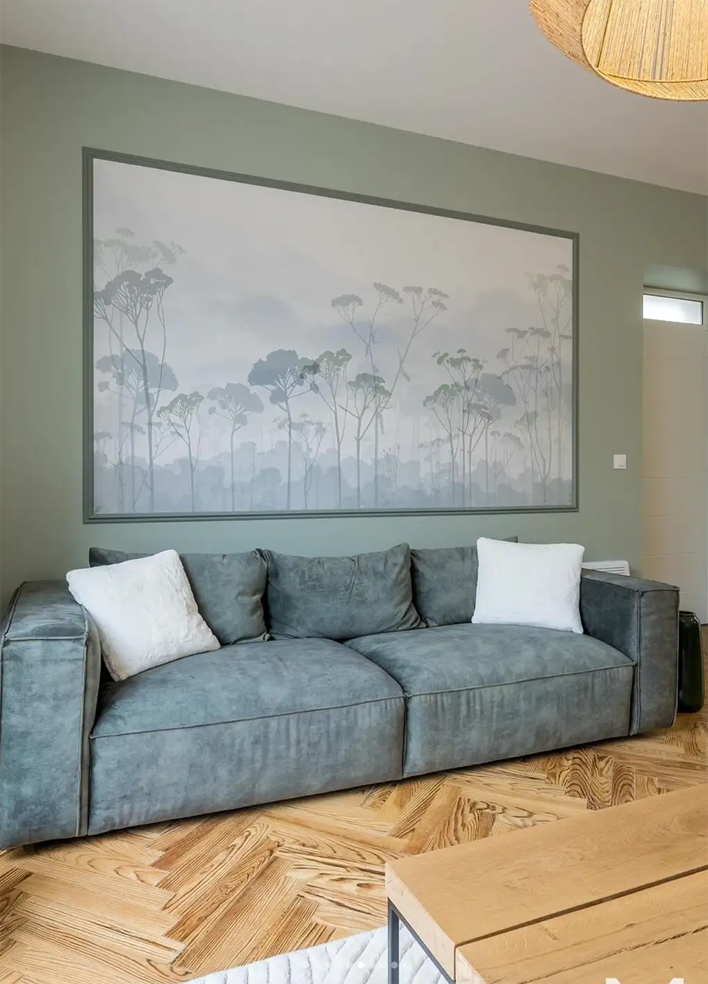 Panoramique Mimizan d'une forêt de pin réalisé sur-mesure comme un tableau au dessus d'un canapé vert, le tout entouré d'un mur vert pour mettre en valeur le décor.
