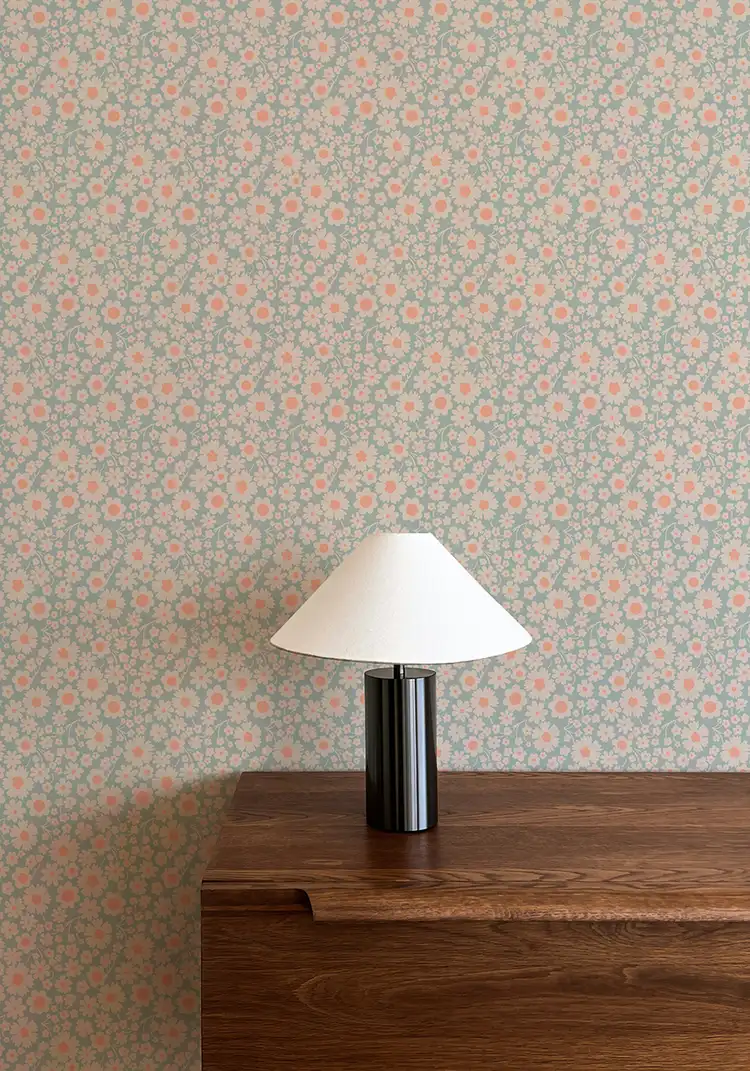 Papier peint floral avec de petites fleurs beiges avec son coeur rose, le tout sur une fond bleu clair pour un effet frais et acidulé.