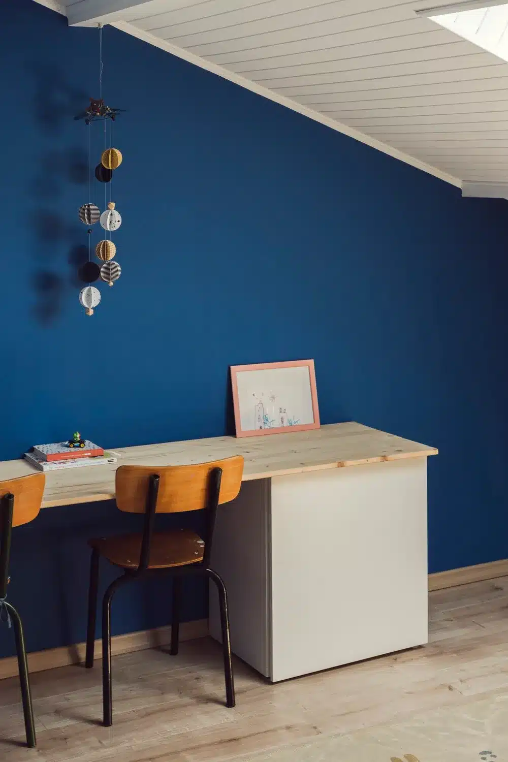 Chambre d'enfant peinte dans un magnifique bleu qui met en valeur le parquet et la décoration colorée aux murs.