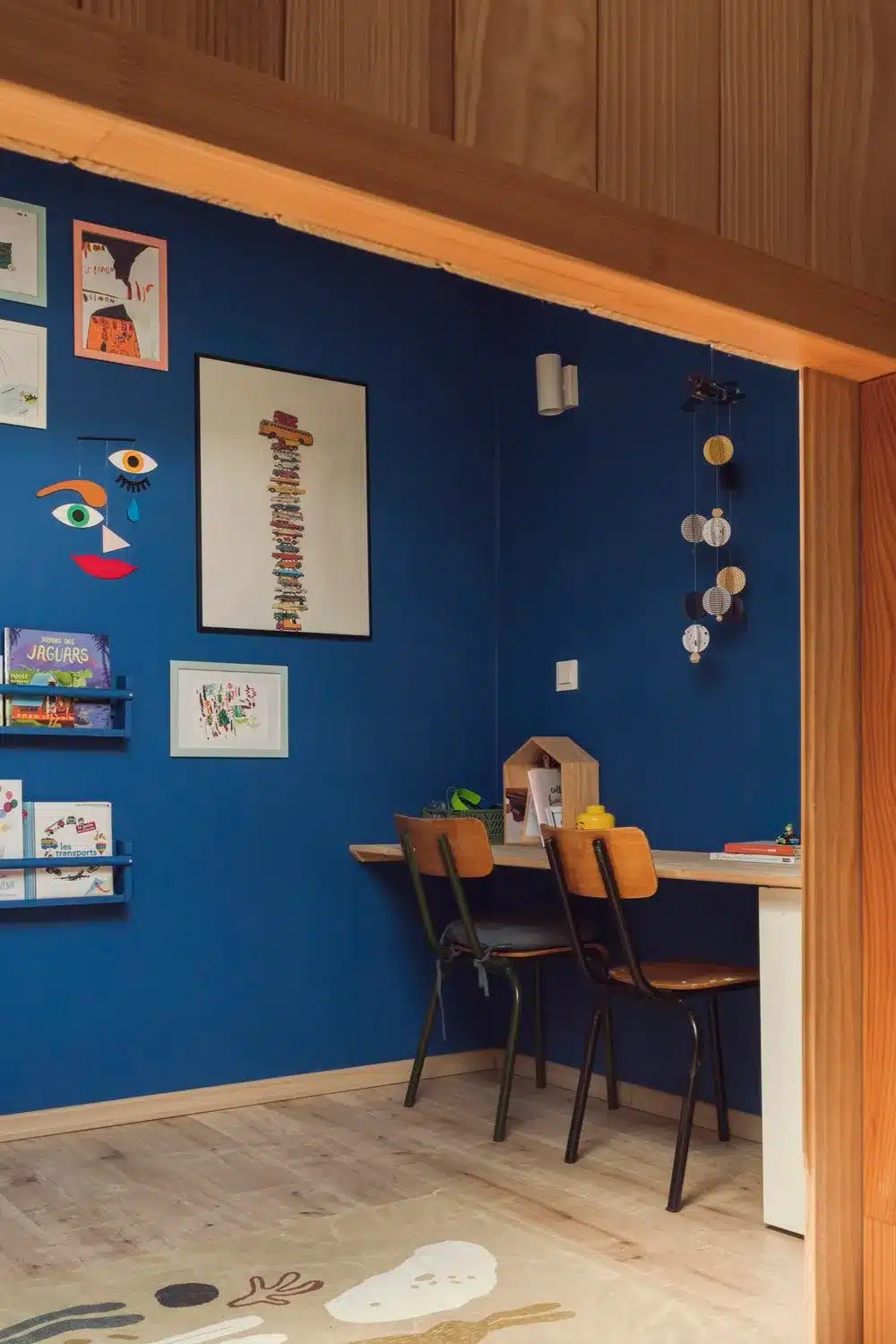 Chambre d'enfant bleue qui met en valeur les tons chaleureux de bois avec ses chaises d'écolier vintage.