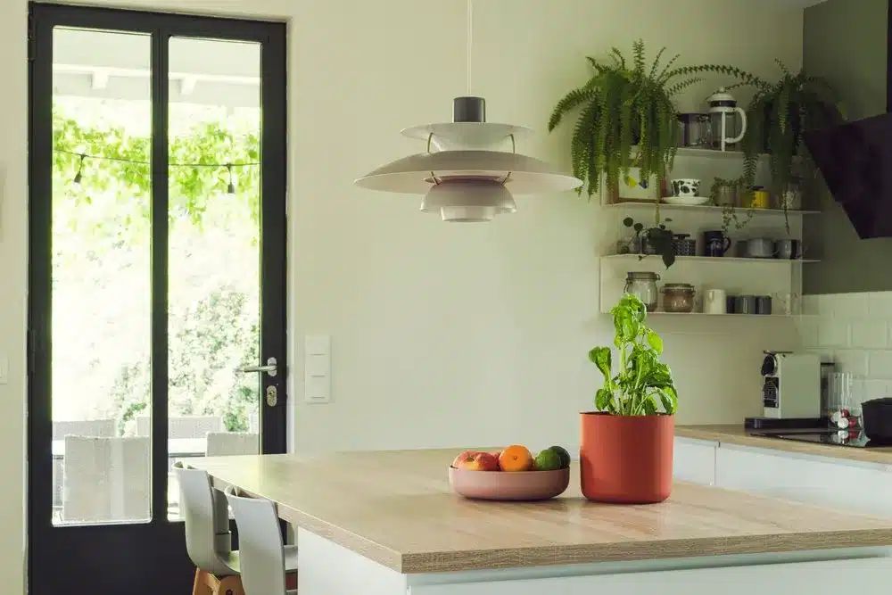 Photo d'une cuisine blanche et bois avec des touches de vert lichen, terracotta et ses fenêtres style verrière atelier.
