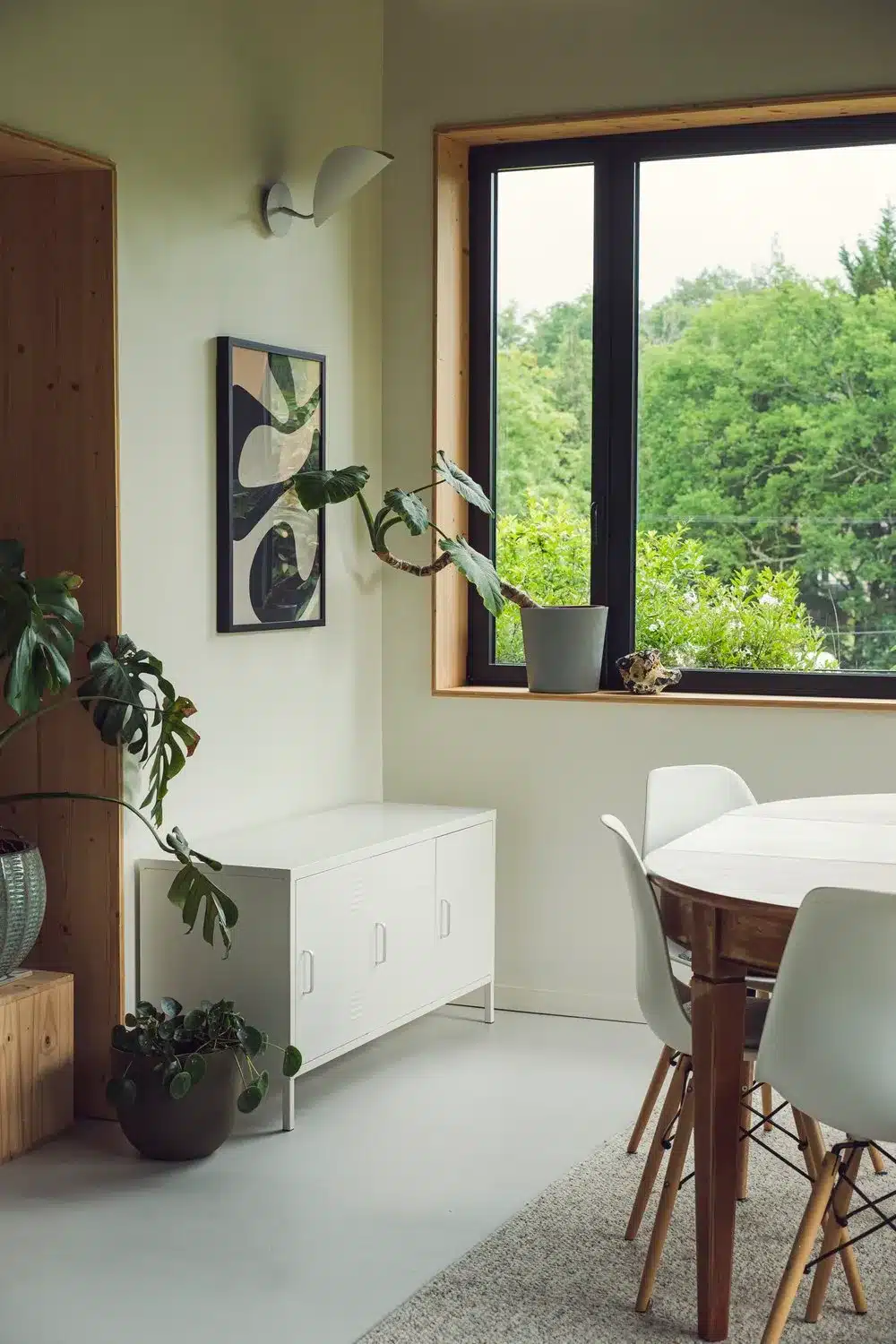 Photo d'un intérieurs lumineux avec ses murs blancs et son sol en béton ciré dans un style scandinave avec ses contours de fenêtres en bois.