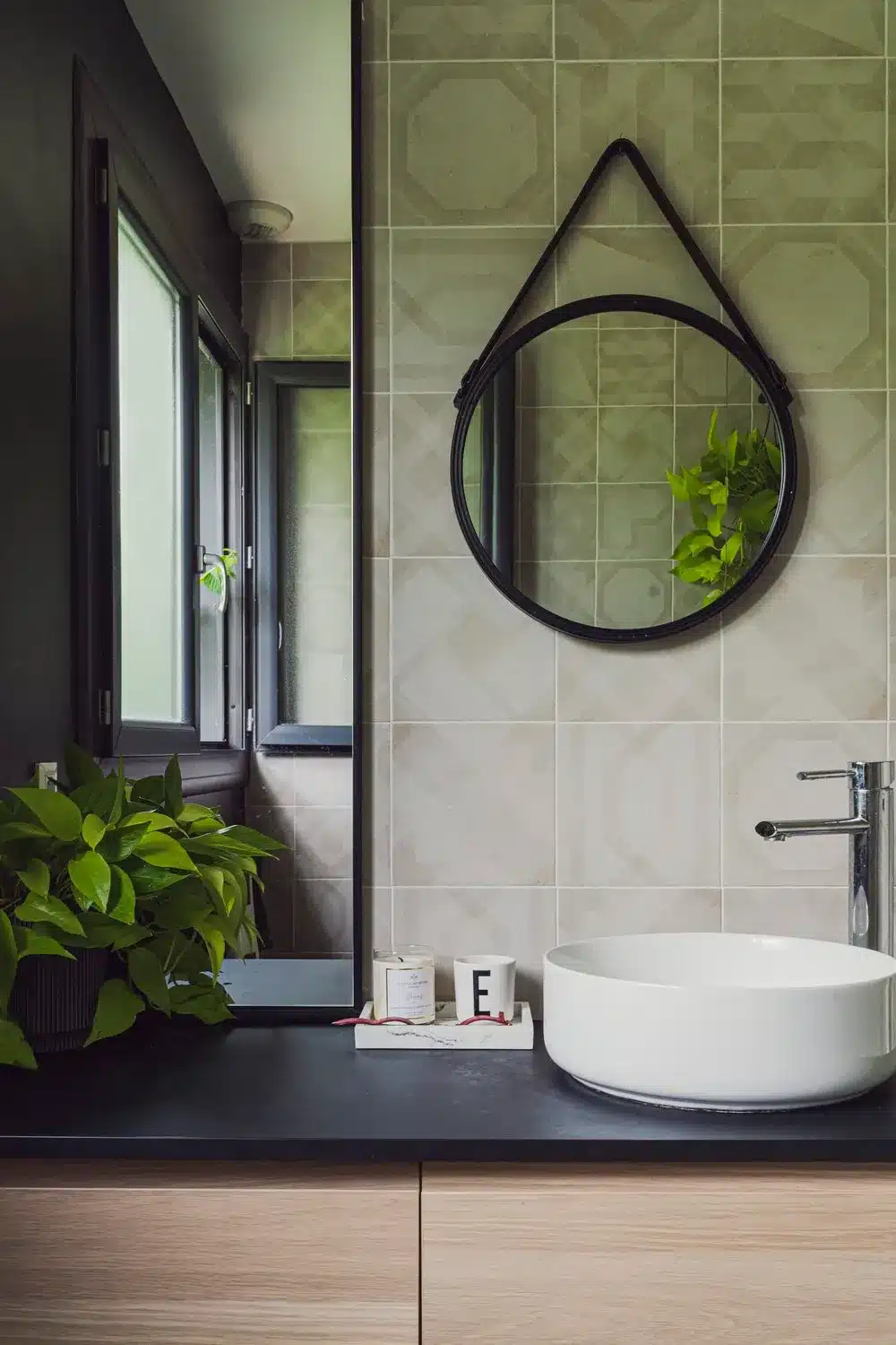 Vasque de salle de bain en bois avec plan de travail noir et sa vasque blanche. L'association de deux miroirs, un grand rectangle et un petit rond donne de l'originalité.