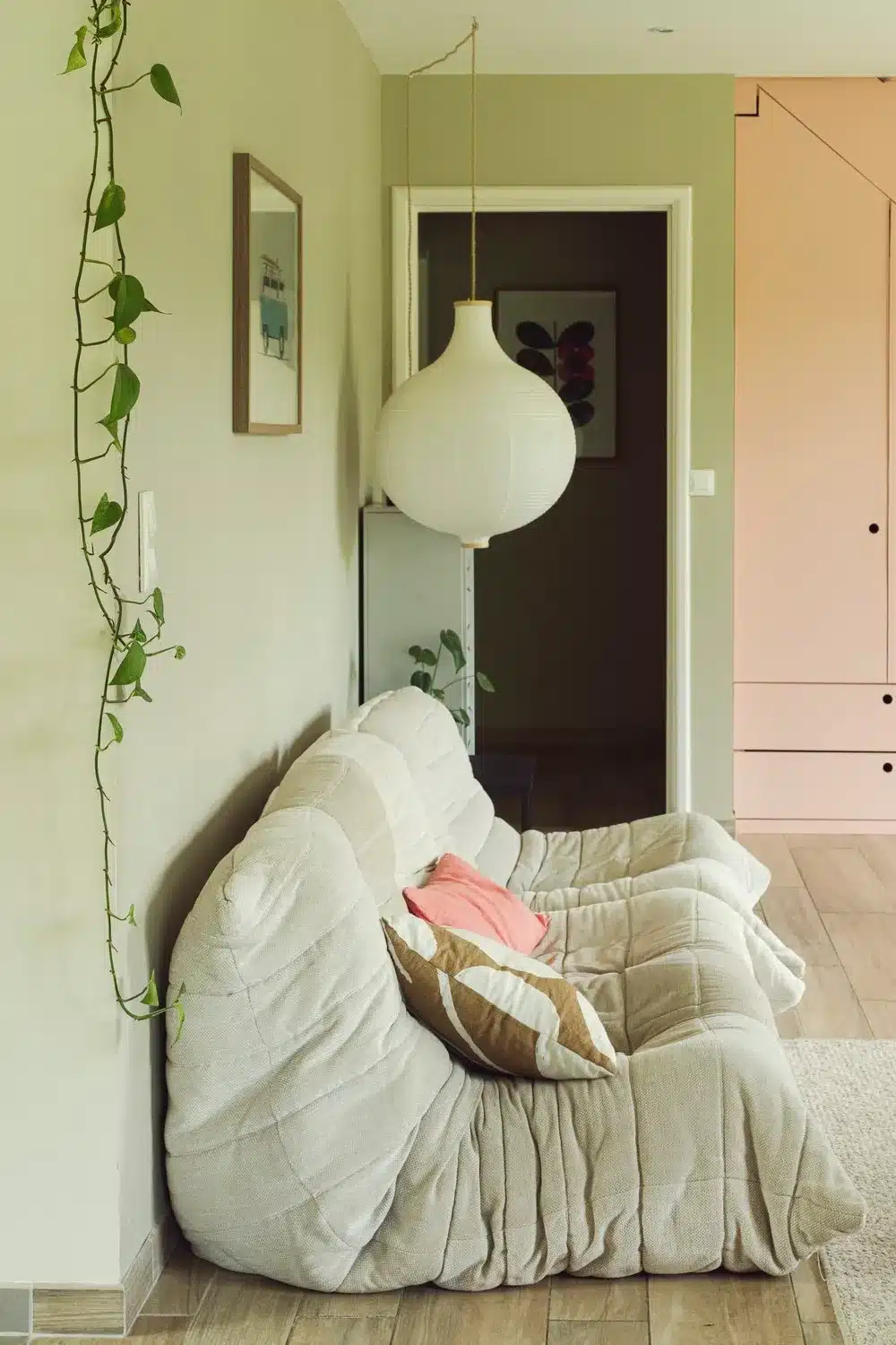 L'emblématique canapé Togo de chez Ligne Roset dans un blanc crème doux dans un salon douillet aux tons de beige et rose.