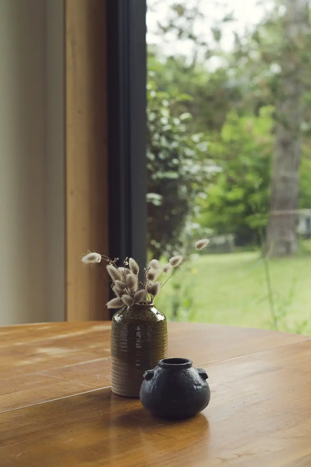 Photo de petits vases fabriqués à la main par un artisan dans un style japonais posés sur une table en bois de famille.