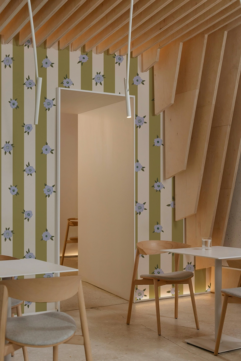 Papier peint à rayures vert pivert et crème avec des jolies fleurs lavandes en surimpression.
