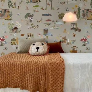 Papier peint au motif enfantin joyeux avec ses petits animaux de la forêt qui sont les personnages au milieu d'un village végétal coloré sur fond café au lait douillet.