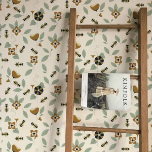 Papier peint éco-conçu au fond beige avec fleurs ocres, feuille vert d’eau et petites abeilles.