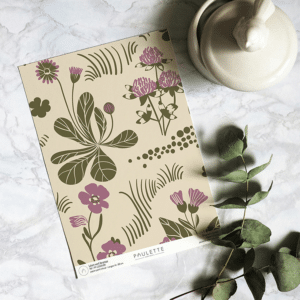 Echantillon de papier peint intissé du motif Léon de fleurs de jardin violet et vert sur fond beige.