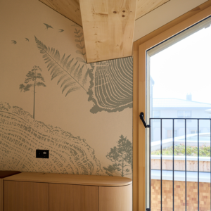 Papier peint panoramique de montagne représentée avec poésie par une tranche de tonc d'arbre, des fougères et se oiseaux qui volent au dessus des crètes.