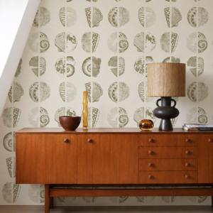 Papier peint Socoa, inspiré de l'océan avec de jolis coquillages et fossiles verts sur fond beige crème.